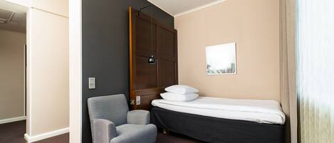 A compact room with a bed, a chair, and a wardrobe.
