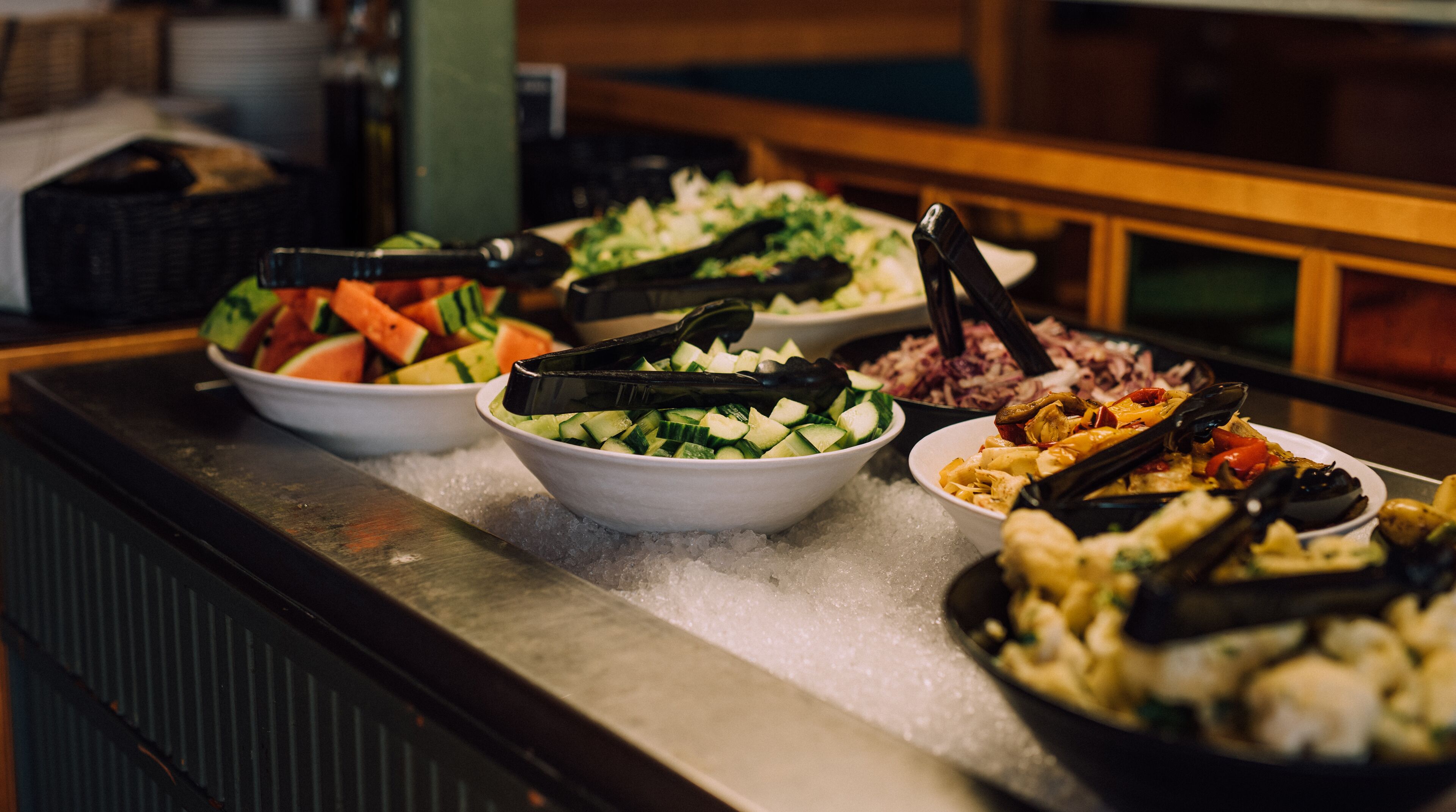 Een buffet met diverse gerechten, waaronder watermeloen, komkommers en zeevruchten.
