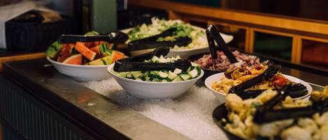 Een buffet met diverse gerechten, waaronder watermeloen, komkommers en zeevruchten.
