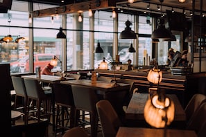 An interior with tables and chairs, pendant lighting, and large windows. - Original Sokos Hotel Vaakuna Joensuu (Joensuu)