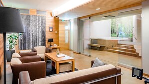 A modern interior with a seating area, a wooden wall, a glass partition, and a view of a pool area. - Original Sokos Hotel Vaakuna Joensuu (Joensuu)