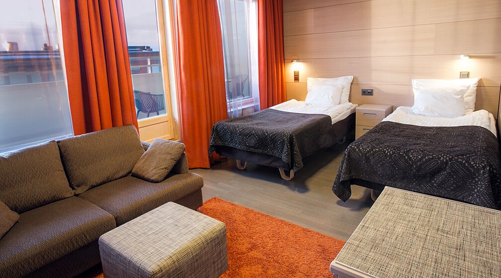 A hotel room with two beds, a sofa, and a small table.