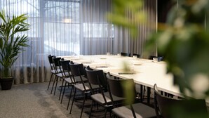 Una sala de conferencias con una larga mesa, sillas y una planta en maceta.