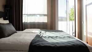 Habitación de hotel con cama, cortinas, ventana y puerta que da a un balcón.