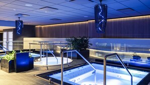 A modern spa area with a hot tub, metal railings, and decorative lighting.