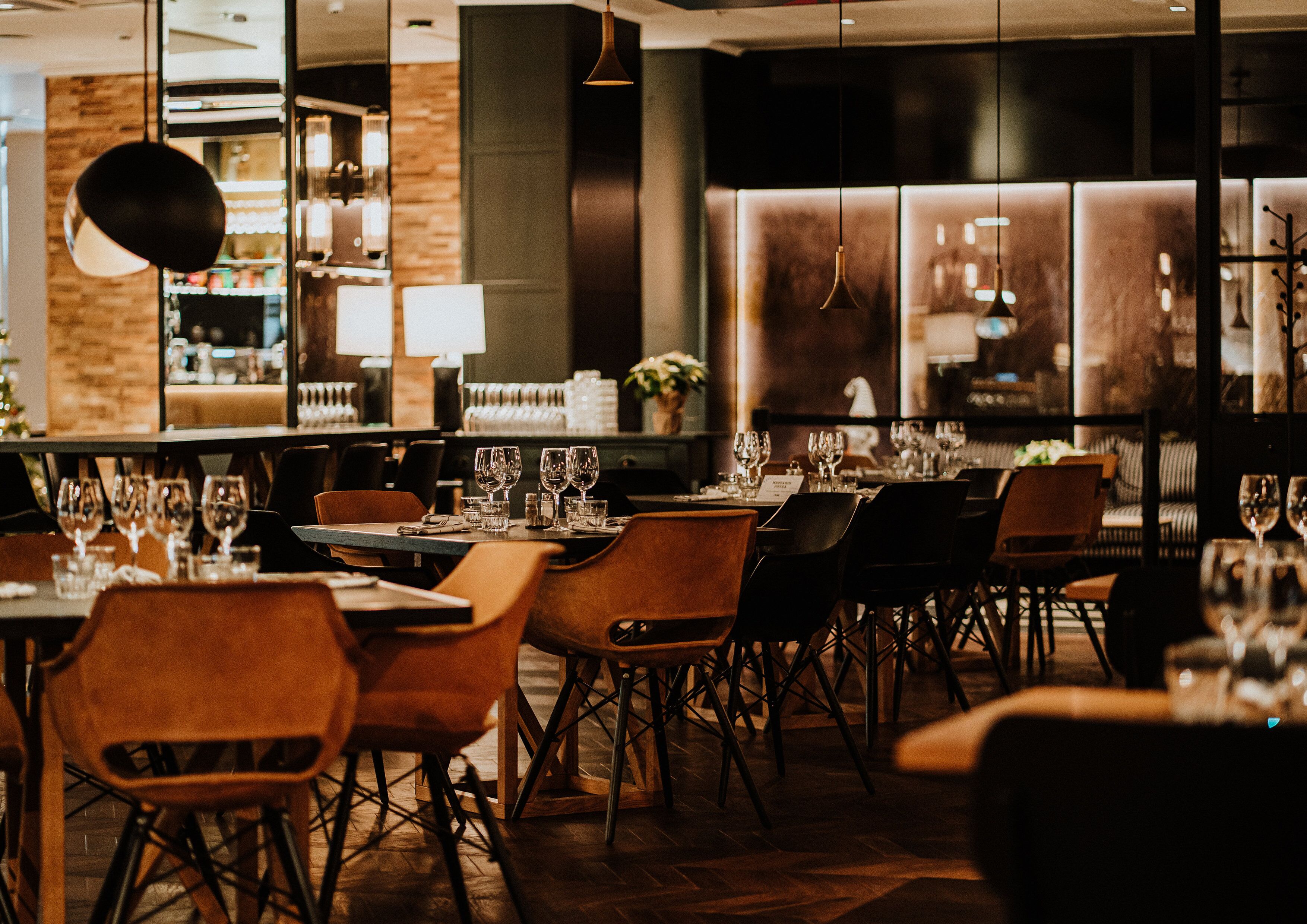 Ein Restaurant mit gedeckten Tischen, Stühlen und hängenden Lampen.