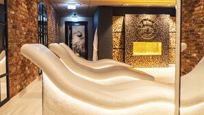 A modern spa area with a brick wall, a large mirror, and a textured white bench.