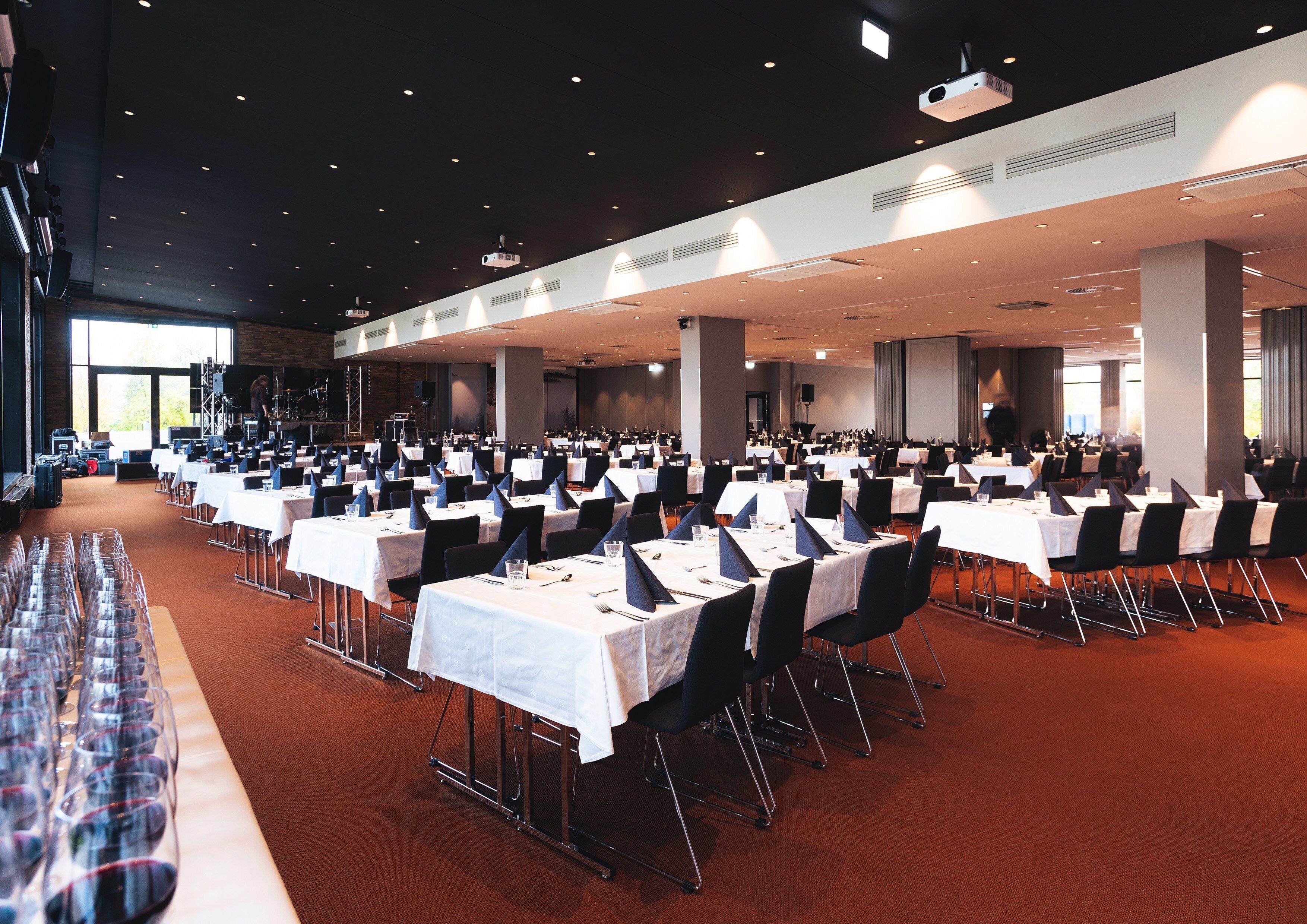 A large banquet hall with rows of tables set for dining, equipped with chairs and table settings.