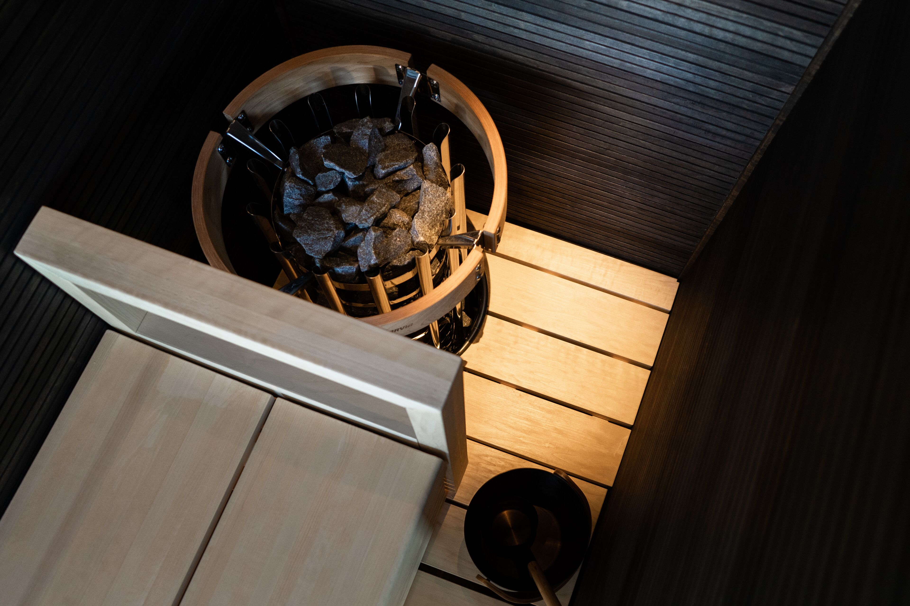 Eine Sauna mit einer Holzbank und einem Steingrundschale.