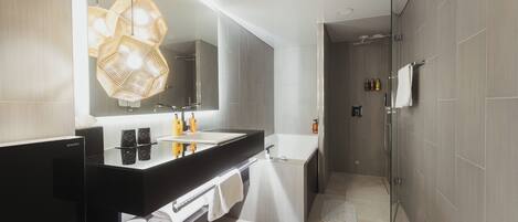 Un baño moderno con un espejo grande, encimera negra y zona de ducha.