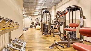 A gym with various exercise machines, a wooden floor, and a wall-mounted rack of dumbbells. - Klaus K Hotel (Helsinki)