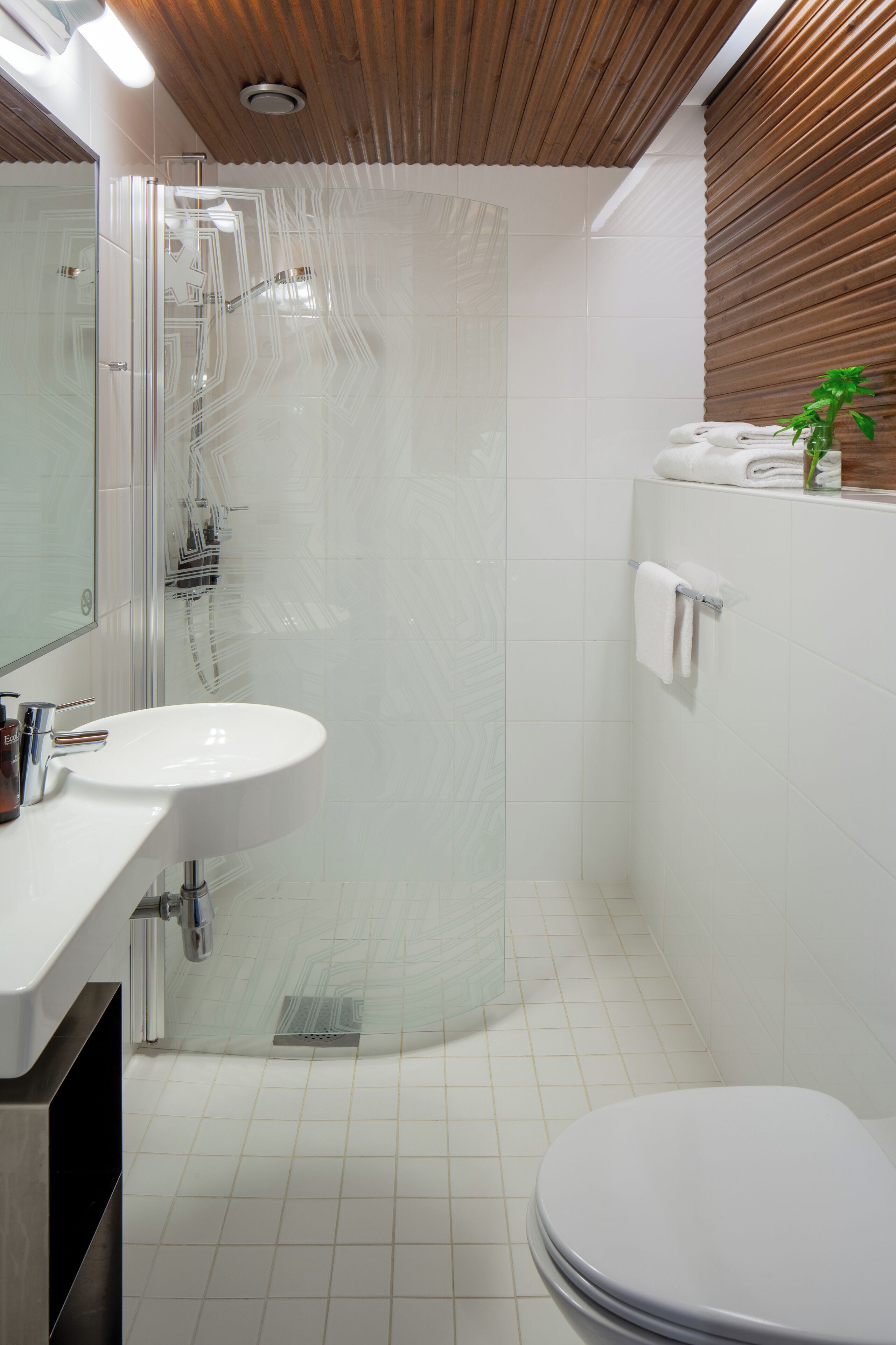 Ein modernes Badezimmer mit Duschkabine aus Glas, einem weißen Waschbecken und einer Toilette.