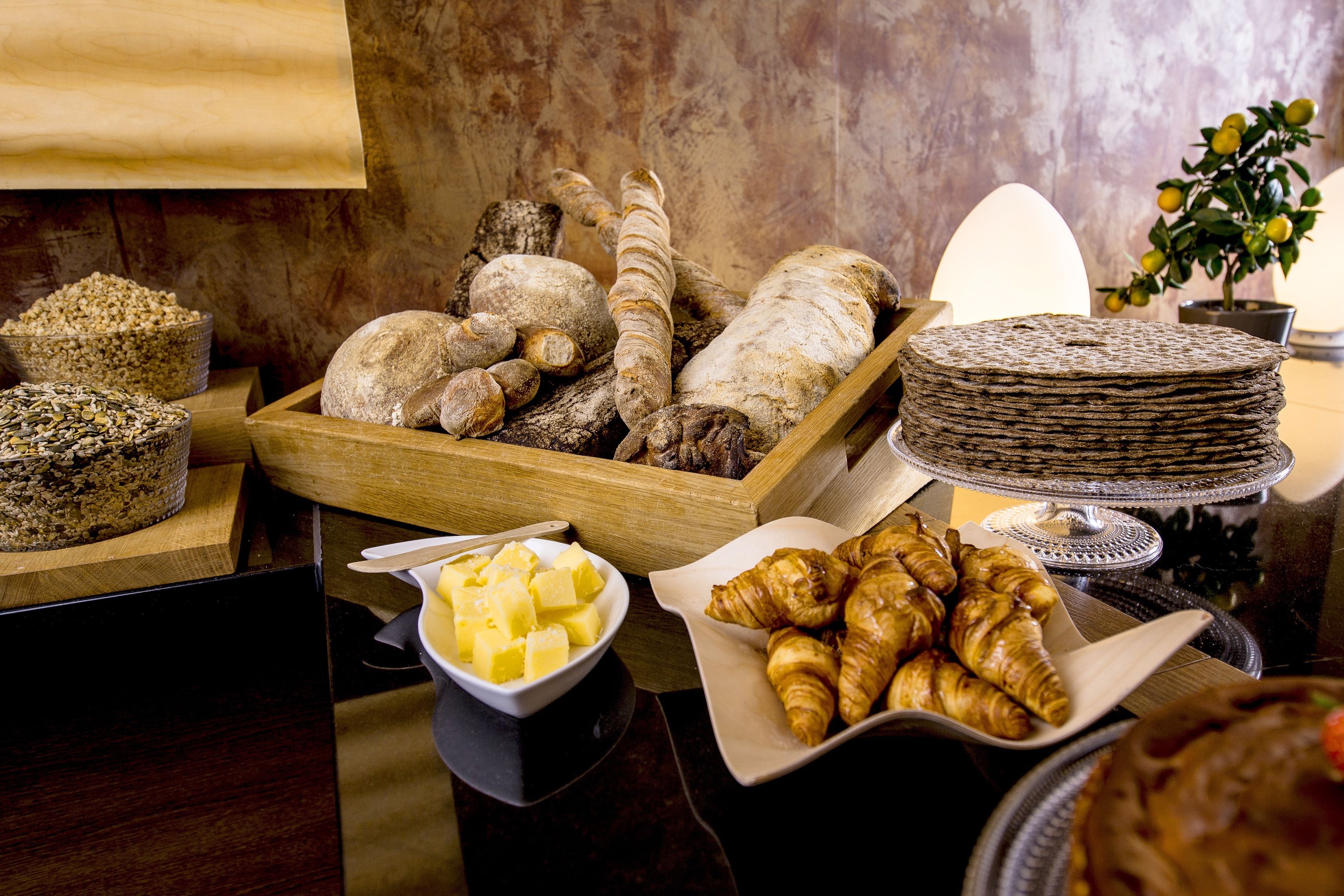 Un buffet proposant une variété de pains, de viennoiseries et un plat de beurre.