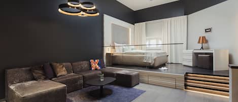Un dormitorio moderno con una cama grande, un sofá, una mesa de centro y una zona de escritorio.
