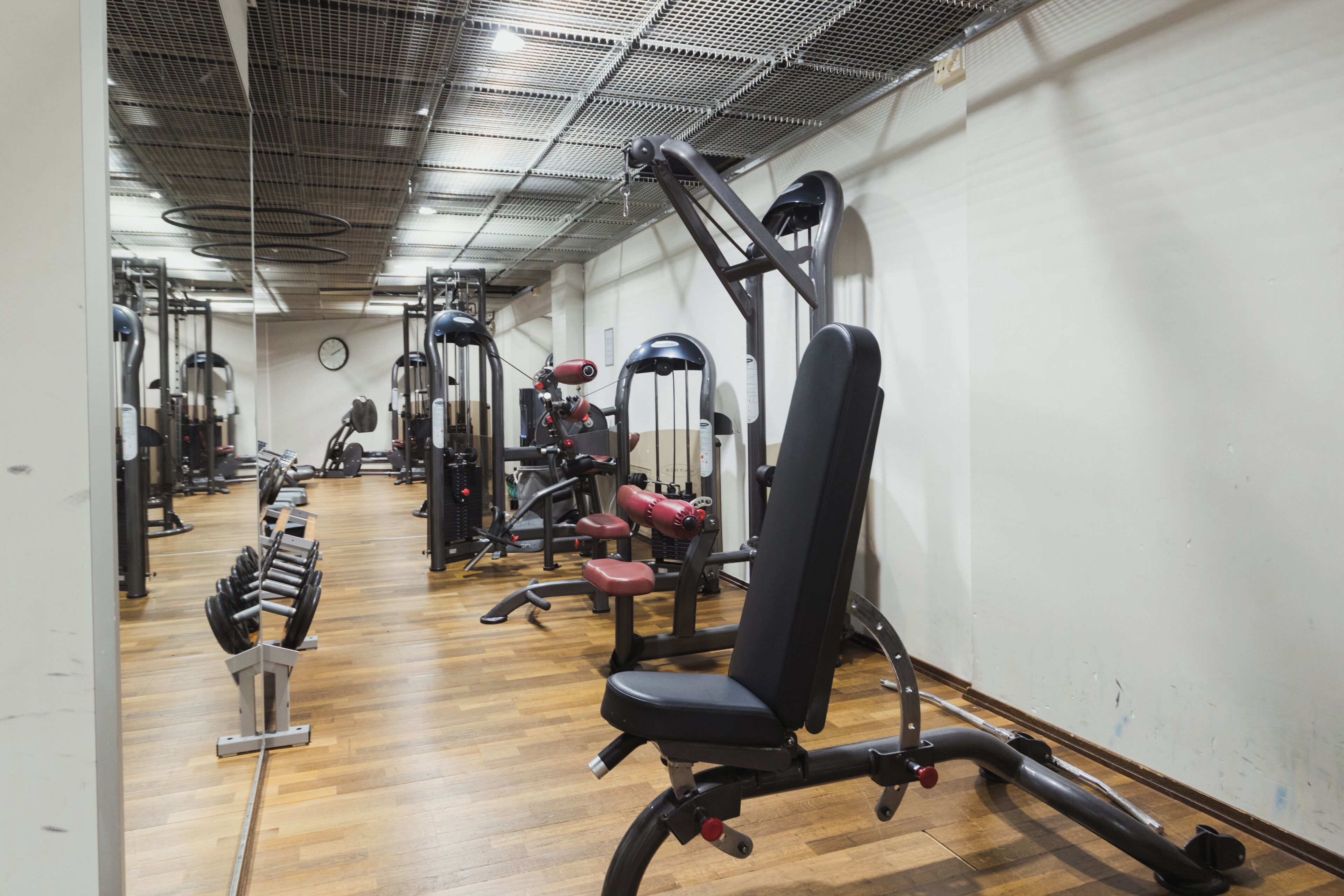 Une salle de sport équipée de divers appareils d’entraînement, notamment des machines de musculation et des haltères.