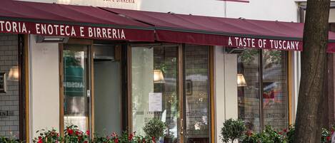 Un restaurante llamado Toscanini con terraza y plantas en macetas.