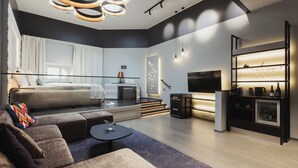 Un soggiorno moderno con un divano, un tavolino da caffè e una TV. Una scala conduce a un balcone.