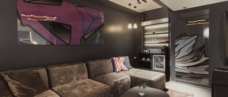 Una sala moderna con un sofá seccional, una mesa de centro y un estante de pared con objetos decorativos.