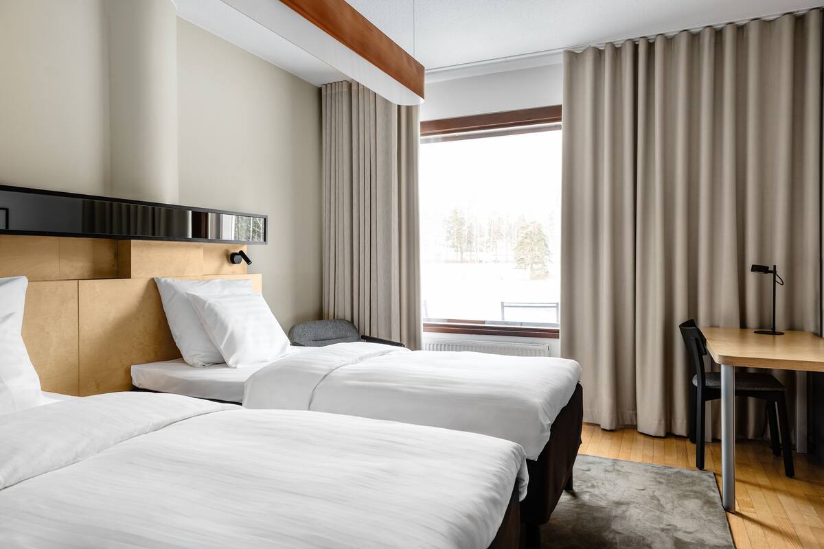 Une chambre d’hôtel avec deux lits, un bureau et une chaise.