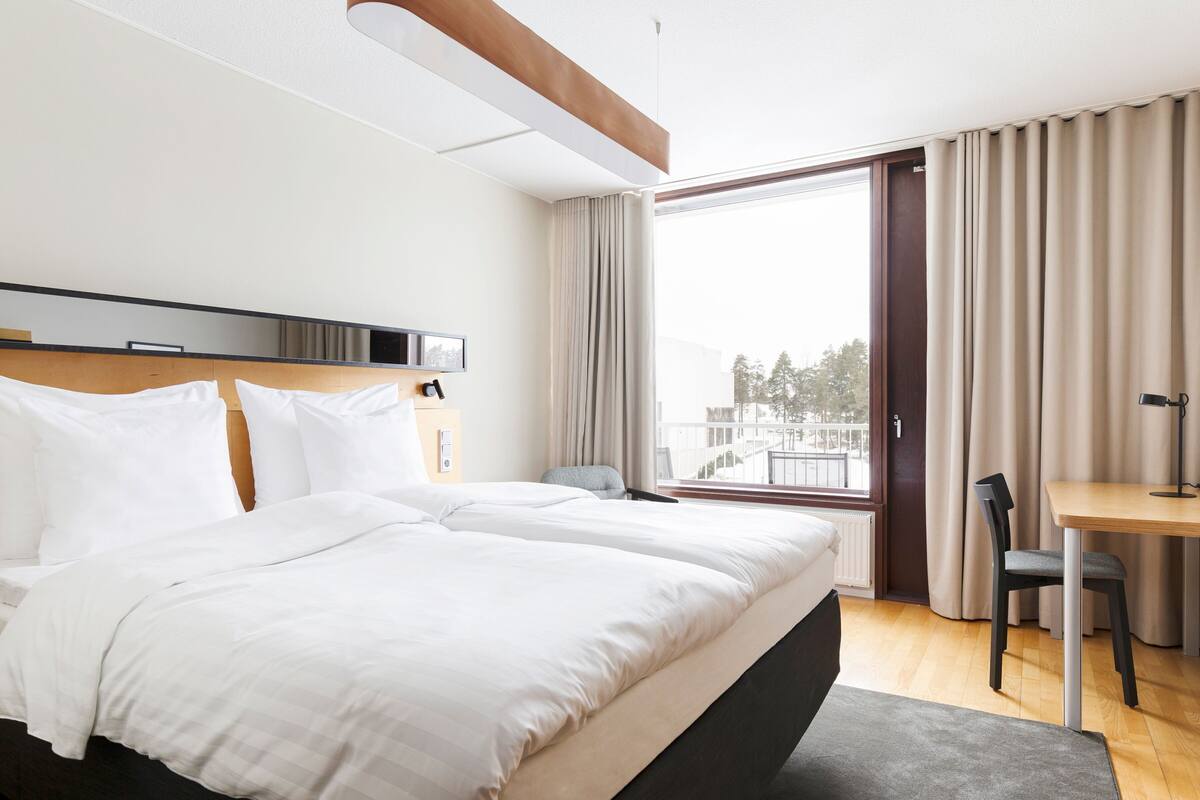 Une chambre d’hôtel avec un grand lit, un bureau et une chaise.