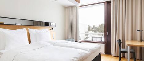 Una habitación de hotel con una cama grande, un escritorio y una silla.