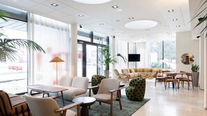 A spacious lobby with modern furniture, large windows, and a flat-screen TV.
