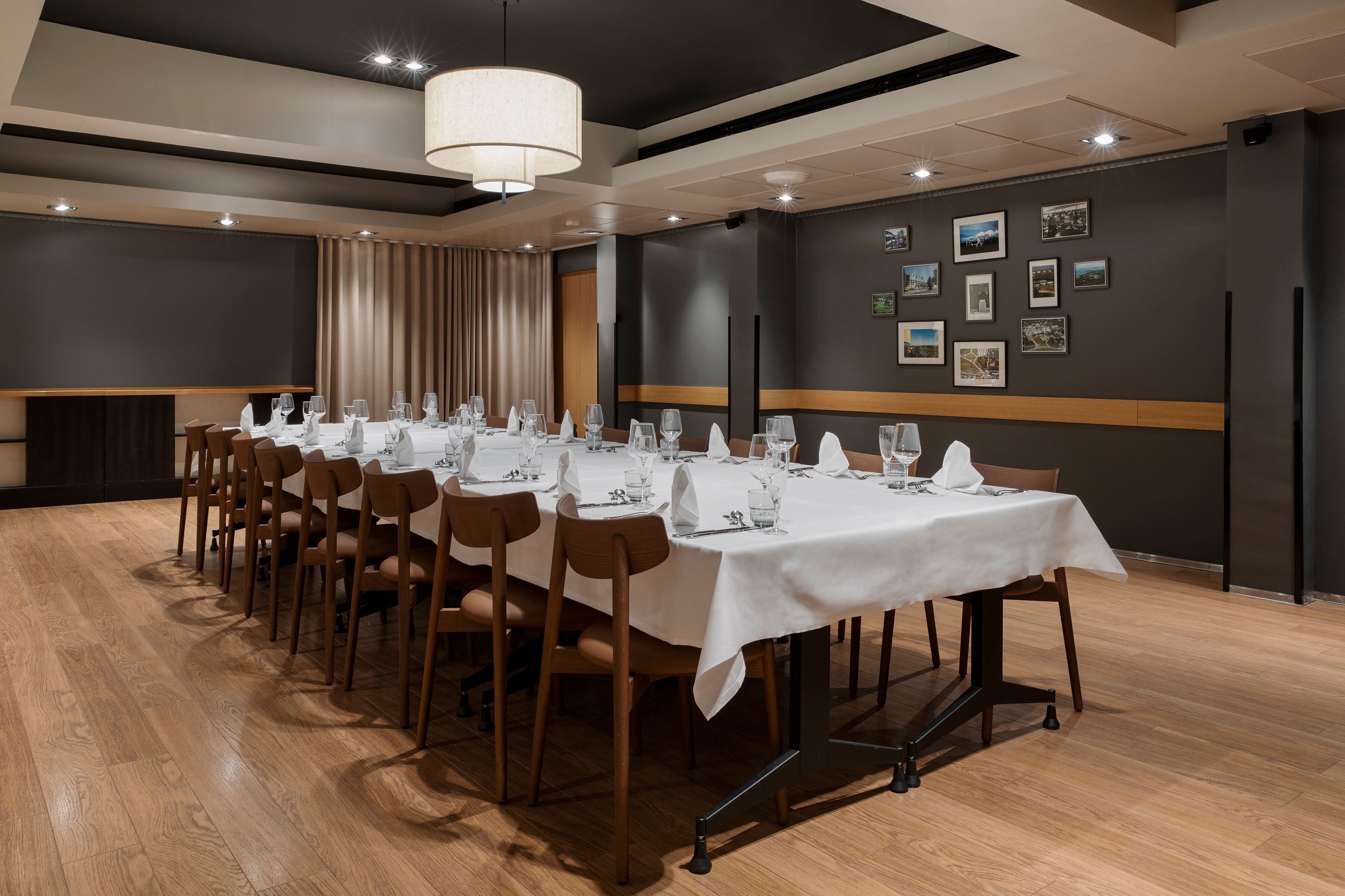 A conference room with a long table set for a meeting, equipped with chairs and a projector screen.