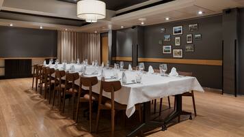 A conference room with a long table set for a meeting, equipped with chairs and a projector screen.