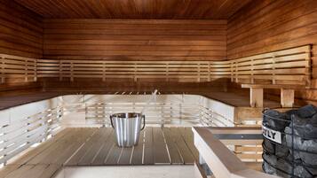 A sauna with wooden benches and a metal bucket.