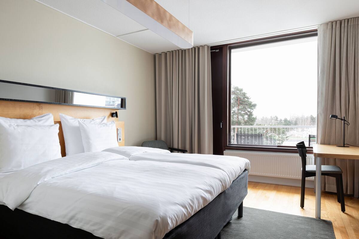 Une chambre d’hôtel avec un grand lit, un bureau et une vue sur l’extérieur.