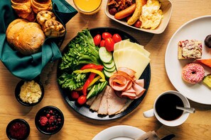 A variety of food items on a table, including bread, vegetables, cheese, and meat. - Original Sokos Hotel Tapiola Garden (Espoo)