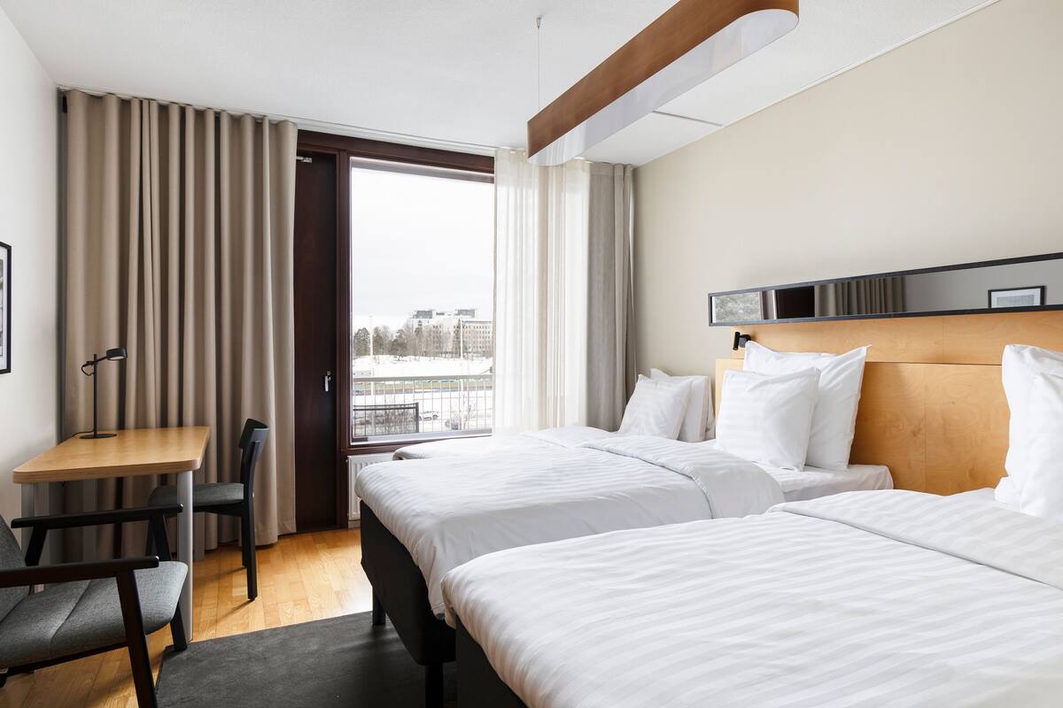 Une chambre d’hôtel avec deux lits, un bureau et des chaises.