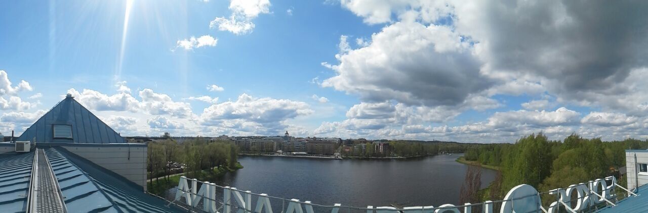 A river with buildings in the background, a clear sky, and a bridge with railings.