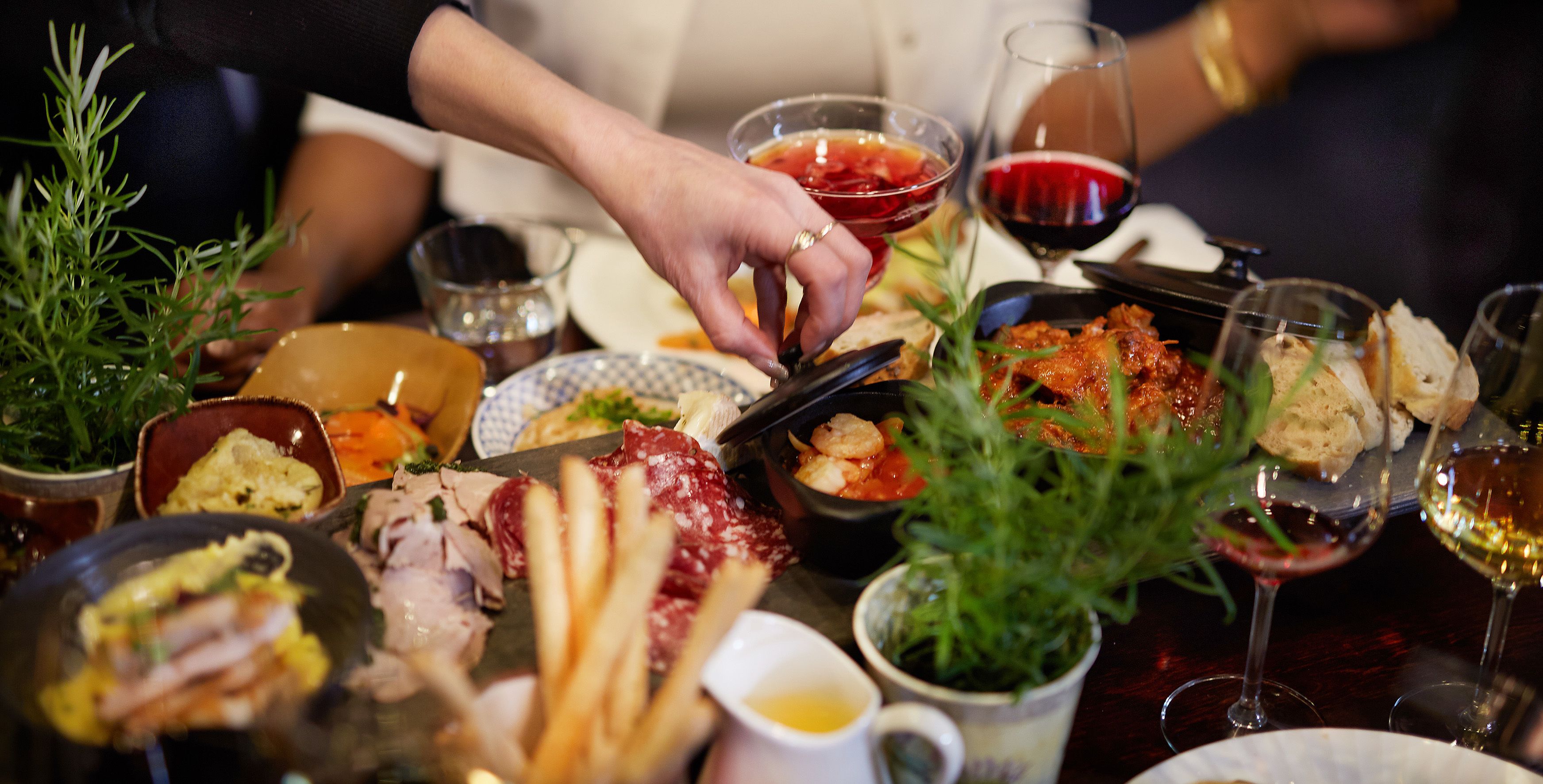 Una mesa con diversos platos, incluyendo carnes, pan y un recipiente pequeño con salsa.
