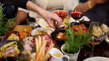 Una mesa con diversos platos, incluyendo carnes, pan y un recipiente pequeño con salsa.