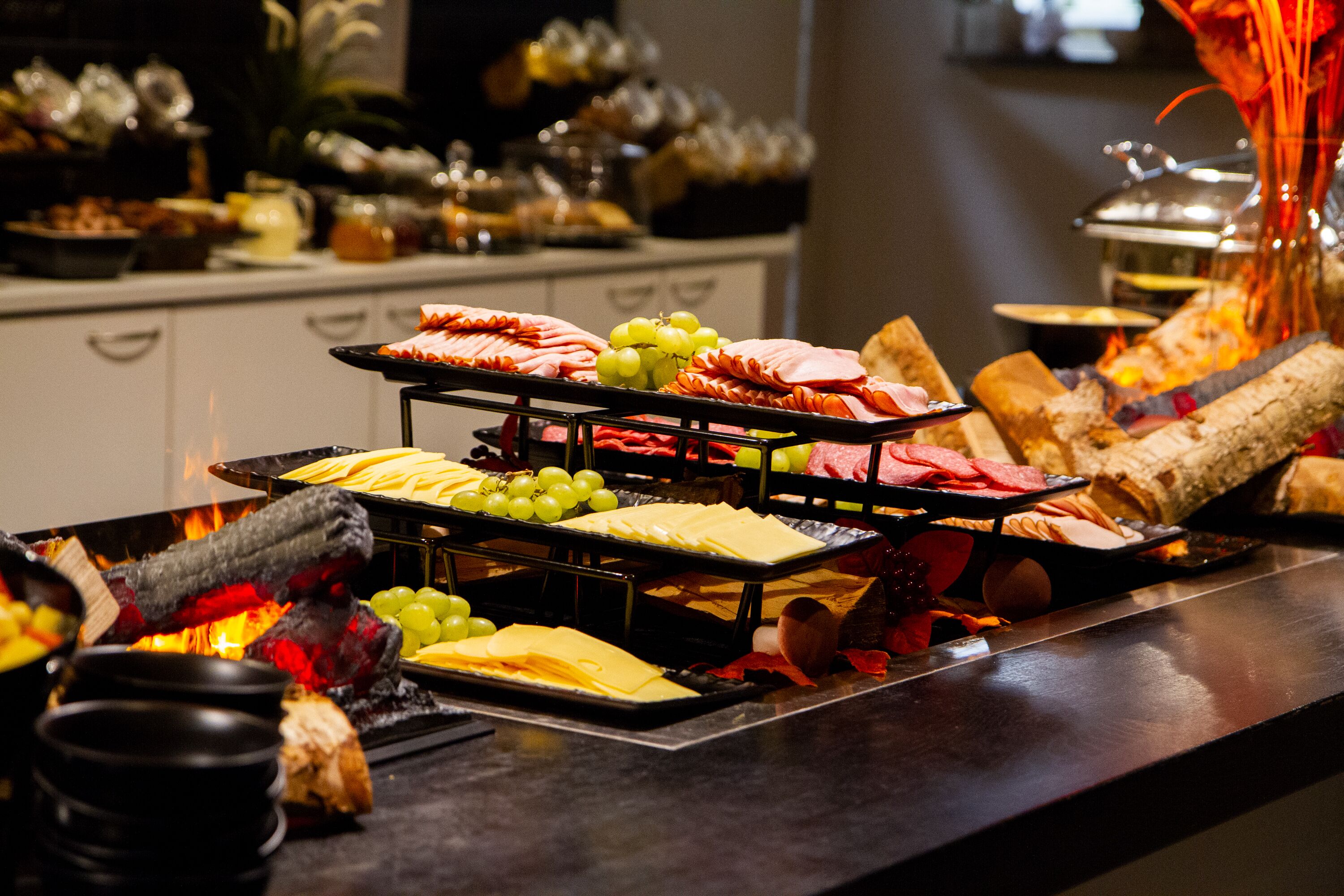 A buffet with various cheeses, meats, and fruits.