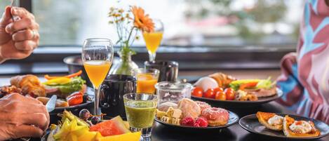 A dining table with various dishes, drinks, and a vase of flowers.