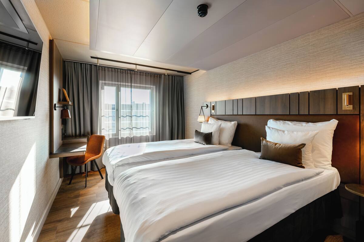 Ein Hotelzimmer mit einem großen Bett, einem Schreibtisch und einem Sessel.