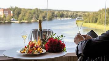 Een tafel met een champagnefles, een wijnglas, een fruitschaal en een boeket rode rozen.