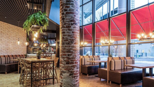 A modern interior with brick walls, wooden flooring, and a large window with red curtains. There are seating areas with tables and chairs. - Original Sokos Hotel Vantaa (Vantaa)