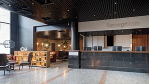 A reception area with a reception desk, seating area with chairs and a sofa, and a bookshelf. - Original Sokos Hotel Vantaa (Vantaa)