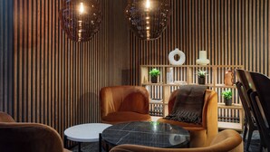 A modern interior with striped wooden walls, leather armchairs, a round table, and pendant lighting. - Original Sokos Hotel Vantaa (Vantaa)