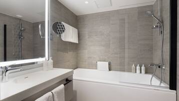 A modern bathroom with a large mirror, a bathtub, and a shower area.