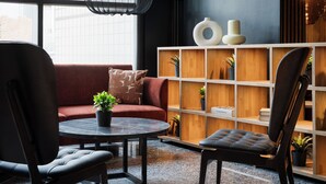 A modern lounge area with a round table, two leather chairs, a red sofa, and a wooden shelving unit with decorative items. - Original Sokos Hotel Vantaa (Vantaa)