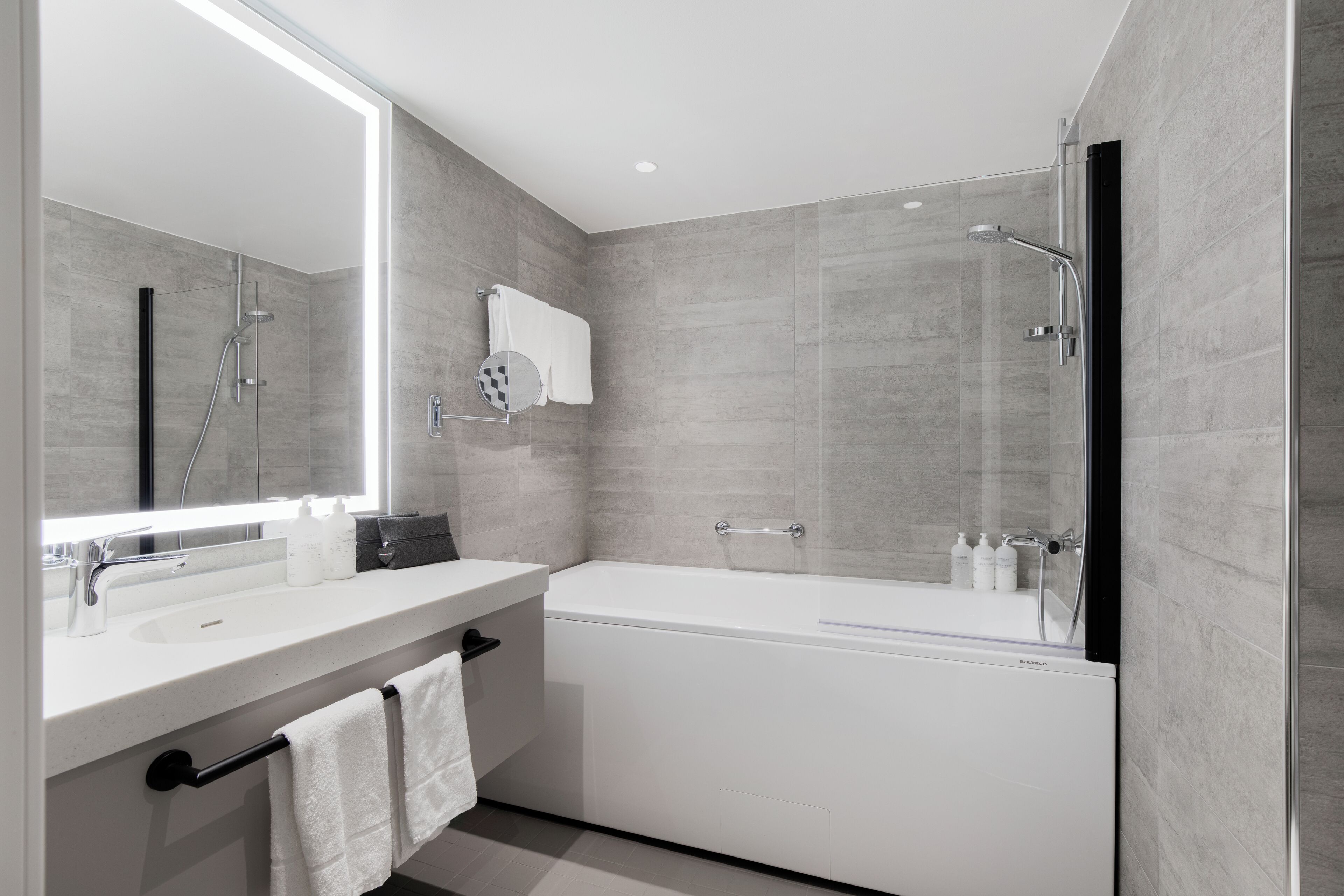 Un baño moderno con un espejo grande, una bañera y una zona de ducha.