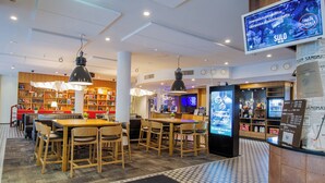 Vestíbulo de hotel con mostrador de recepción, zona de estar y una amplia estantería.