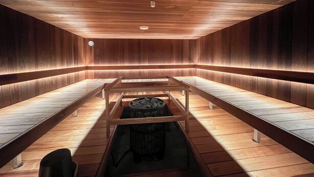 Un cuarto de sauna con bancos de madera y un calentador central.