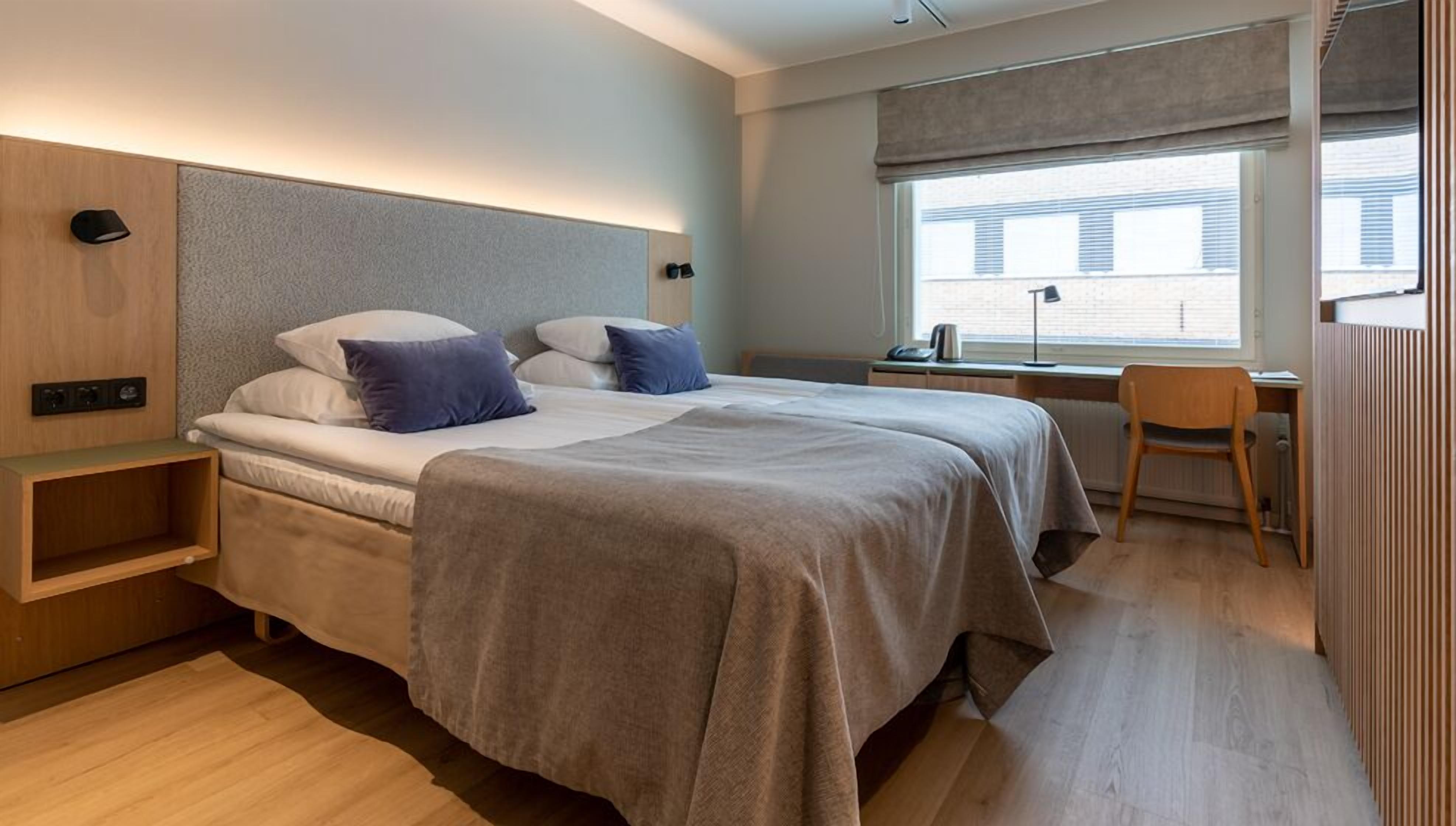 Une chambre moderne avec un grand lit, des tables de chevet, un bureau et une chaise.