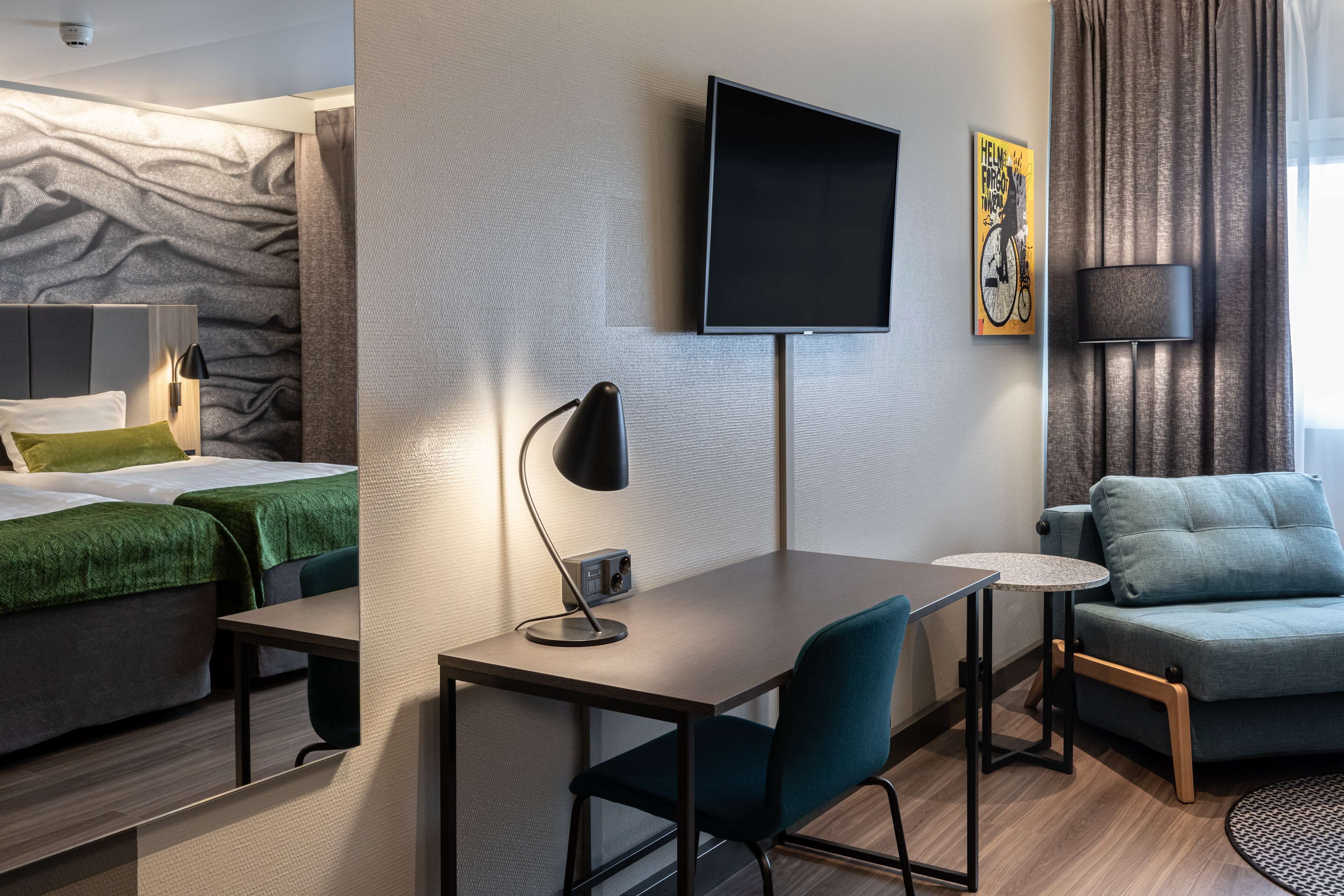 Una habitación de hotel moderna con cama, escritorio, silla, televisor y sofá.