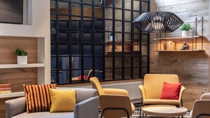 A modern lounge area with sofas, a round table, and a geometric pendant light. - Scandic Pasila (Helsinki)